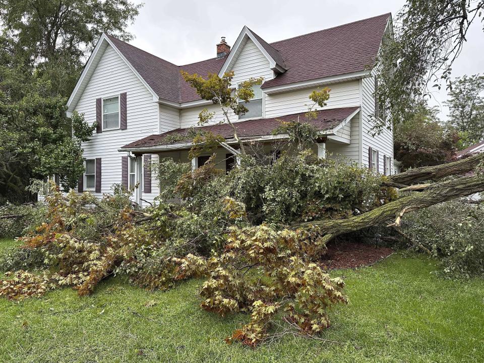 A tree is uprooted outside a home on Friday, Aug. 25, 2023, in Canton Township, Mich. A strong storm powered by winds of up to 75 mph (121 kph) in Michigan downed trees, tore roofs off buildings and left hundreds of thousands of customers without power. (AP Photo/Mike Householder)