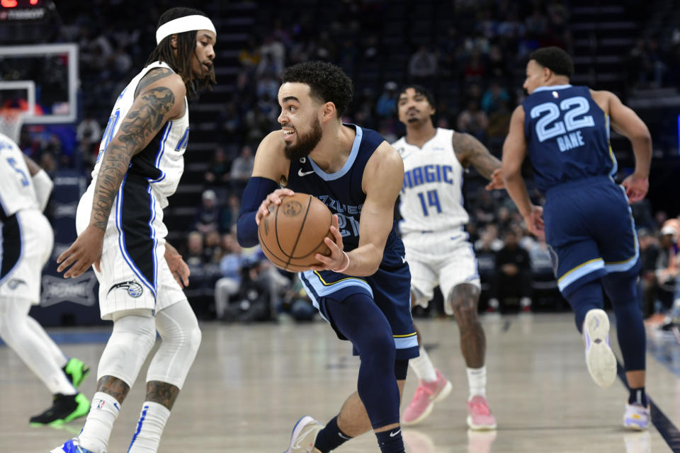 Memphis Grizzlies guard Tyus Jones (21) handles the ball ahead of Orlando Magic center Moritz Wagner, left, in the first half of an NBA basketball game Tuesday, March 28, 2023, in Memphis, Tenn. (AP Photo/Brandon Dill)