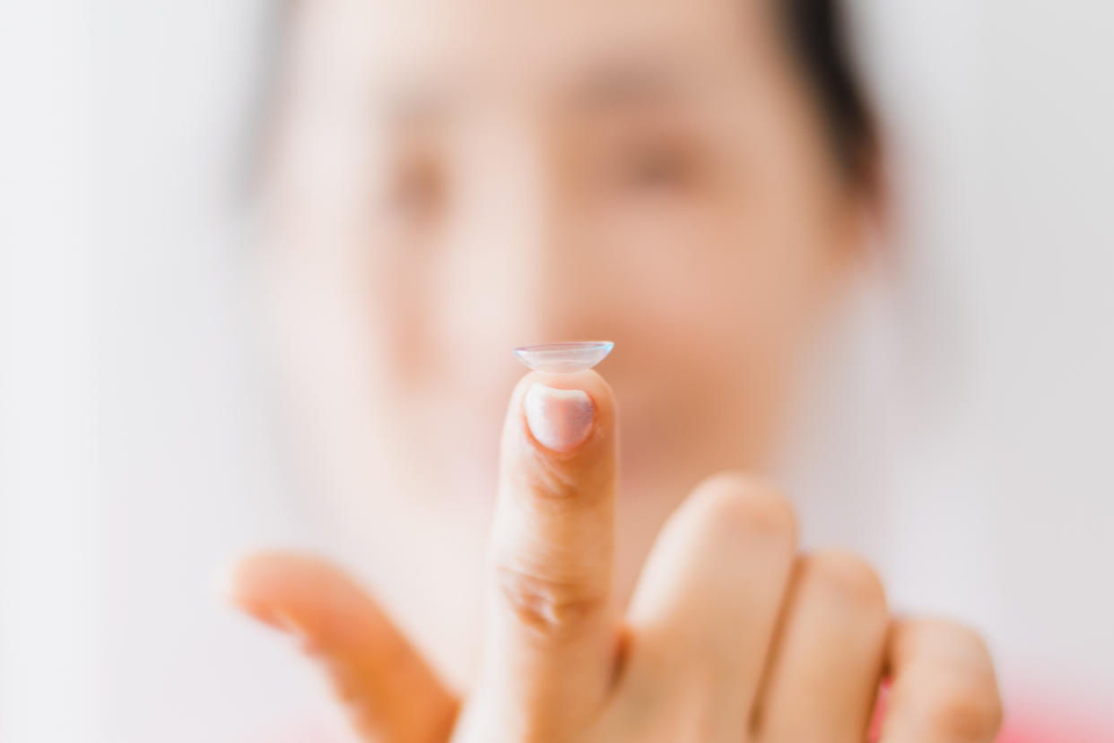 Woman putting eye lenses with hands. (Photo: Getty)