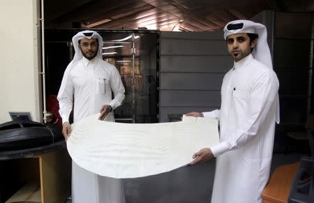 Mechanical engineers Abdullah Mojeb Aldar (L), 26, and Fahad al-Musalam, 24, hold up a panel of a 3D printed World Cup stadium model as it is tested at a laboratory at Qatar University in Doha, Qatar June 16, 2016. REUTERS/Ibraheem Al Omari