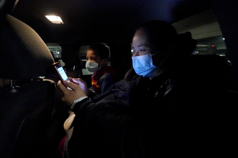 Celestina Ramirez, right, a migrant from Honduras, and her son, Yancarlos Amaya, 5, sit in the vehicle of family friend Dimas Barahona after Ramirez was reunited with her brother at Baltimore-Washington International Thurgood Marshall Airport, in Linthicum, Md., Wednesday, March 24, 2021. The siblings had not seen each other in 14 years. (AP Photo/Julio Cortez)