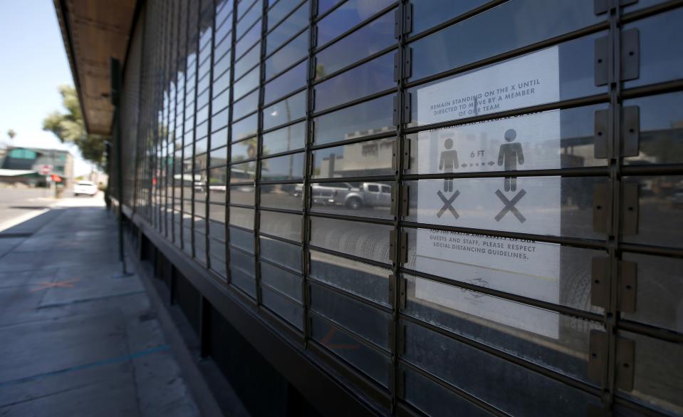 The Riot House, one of the restaurant bars closed for the next 30 days due to the surge in coronavirus cases, even as the social distancing sign is placed in a window Tuesday, June 30, 2020, in Scottsdale, Ariz. (AP Photo/Ross D. Franklin)