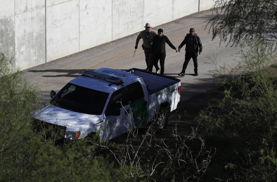 FILE - In this Nov. 16, 2016, file photo, a U.S. Customs and Border Patrol agent walks with suspected immigrants caught entering the country illegally along the Rio Grande in Hidalgo, Texas. While the Trump administration focuses attention on migrant caravans trying to cross the southern U.S. border in California, migration is surging at the opposite end of the border in South Texas. (AP Photo/Eric Gay, File)