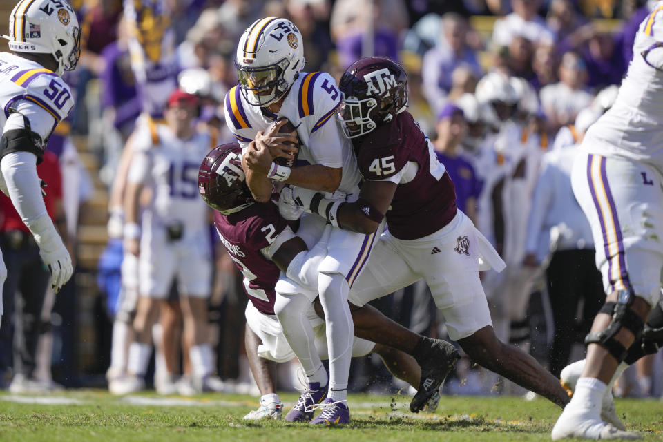 LSU quarterback Jayden Daniels (5) is sacked by Texas A&M linebacker Edgerrin Cooper (45) and defensive back Jacoby Mathews (2) in the first half of an NCAA college football game in Baton Rouge, La., Saturday, Nov. 25, 2023. (AP Photo/Gerald Herbert)