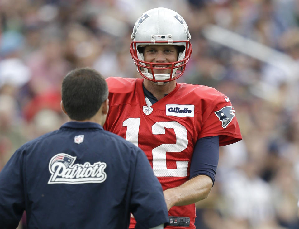 New England Patriots quarterback Tom Brady, right, smiles while working out on the field during an NFL football training camp practice at Gillette Stadium, Sunday, July 27, 2014, in Foxborough, Mass. (AP Photo/Steven Senne)