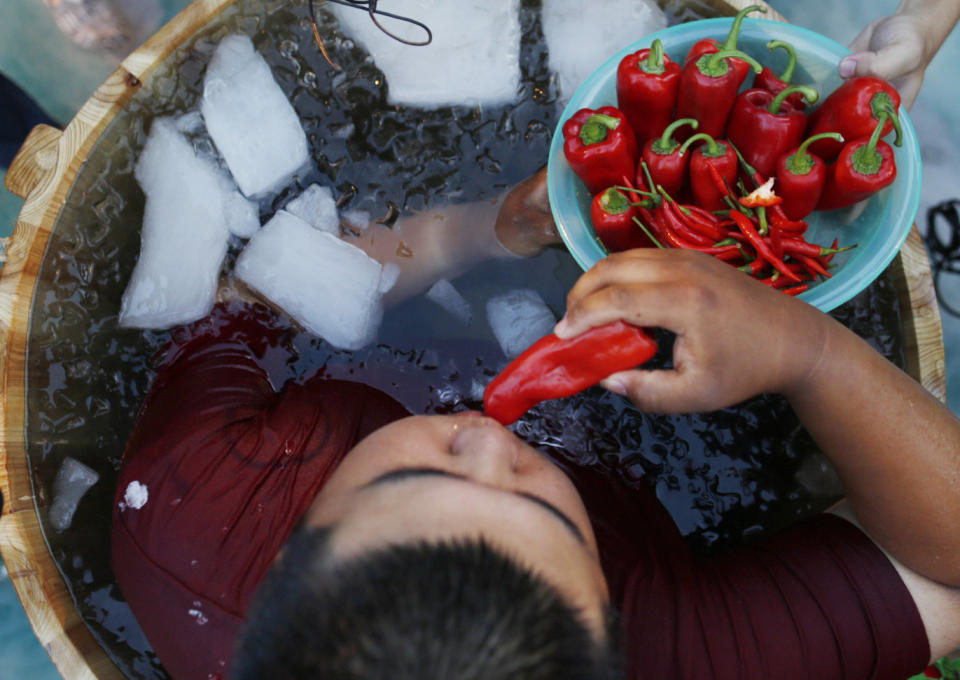A man sitting in an ice bucket eats peppers during a competition at Song Dynasty Town on July 20, 2016 in Hangzhou, Zhejiang Province of China.&nbsp;