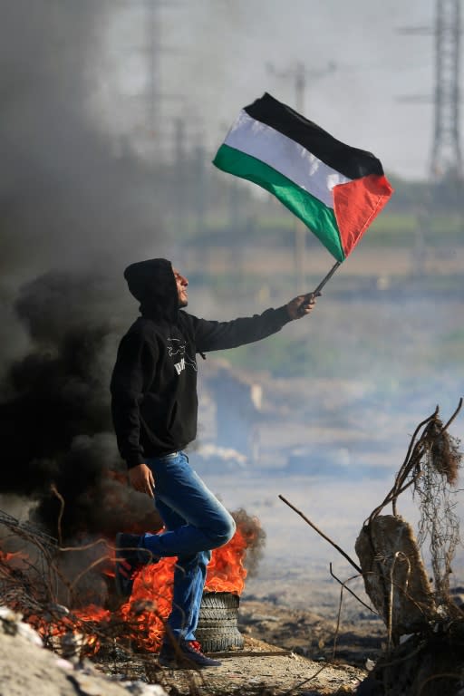 A Palestinian protester waves his national flag during clashes with Israeli security forces along the border with Israel on the eastern outskirts of Gaza City on November 27, 2015