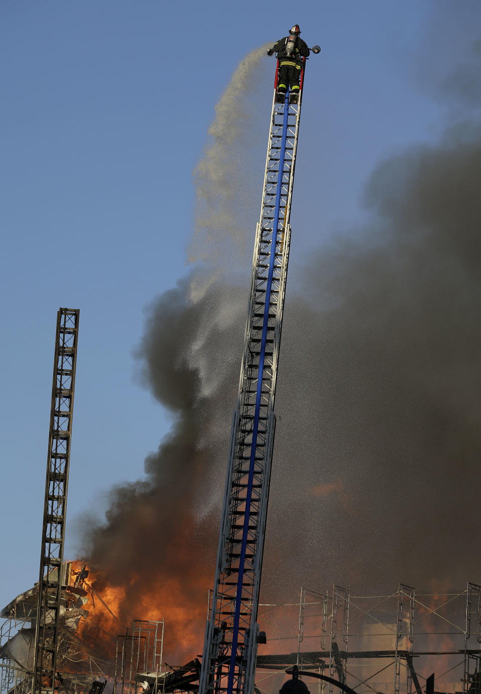 A firefighter sprays water from a hose onto a fire in San Francisco, Tuesday, March 11, 2014. (AP Photo/Jeff Chiu)