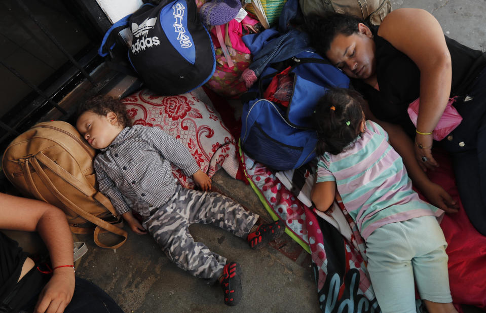 Migrantes hondureños descansan mientras esperan para cruzar la frontera a México, en Tecun Uman, Guatemala, el 17 de enero de 2020. (AP Foto/Marco Ugarte)