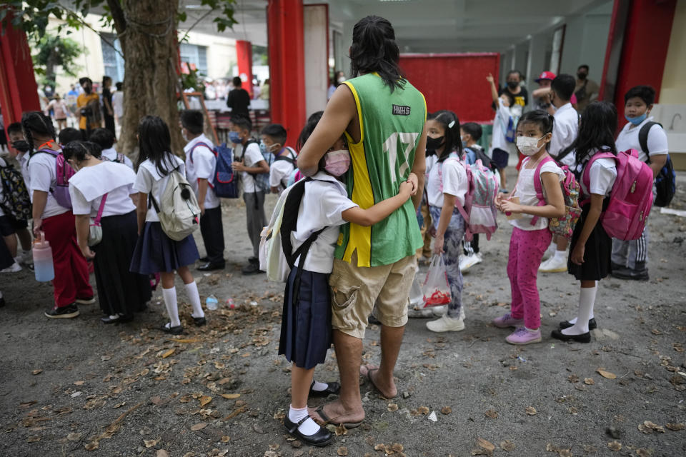 A girl holds on to his father during the opening of classes at the San Juan Elementary School in metro Manila, Philippines on Monday, Aug. 22, 2022. Millions of students wearing face masks streamed back to grade and high schools across the Philippines Monday in their first in-person classes after two years of coronavirus lockdowns that are feared to have worsened one of the world's most alarming illiteracy rates among children. (AP Photo/Aaron Favila)