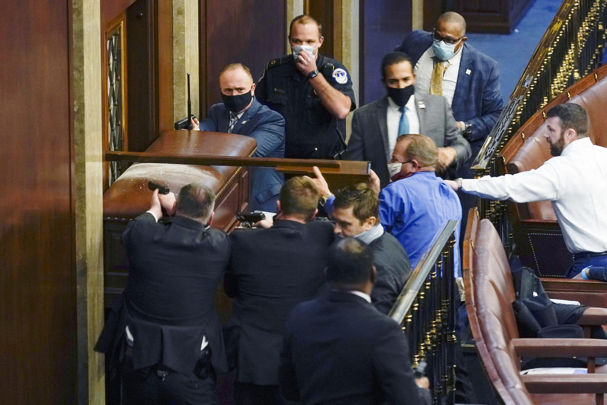 Image: Capitol Police with guns drawn stand near a barricaded door as protesters try to break into the House Chamber on Jan. 6, 2021. (Andrew Harnik / AP file)