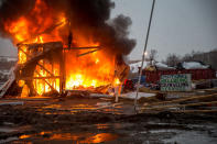 <p>A building burns after it was set on fire by protesters preparing to evacuate the main opposition camp against the Dakota Access oil pipeline, near Cannon Ball, N.D., Feb. 22, 2017. (Photo: Mcknight/Rex Shutterstock via ZUMA Press) </p>