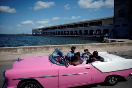 A vintage car with tourists passes by the cruise ships terminal in Havana