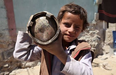 A boy holds a shell which landed which landed from a nearby missile base after the base was struck by a Saudi-led coalition air strike, near Sanaa, April 23, 2015. REUTERS/Mohamed al-Sayaghi