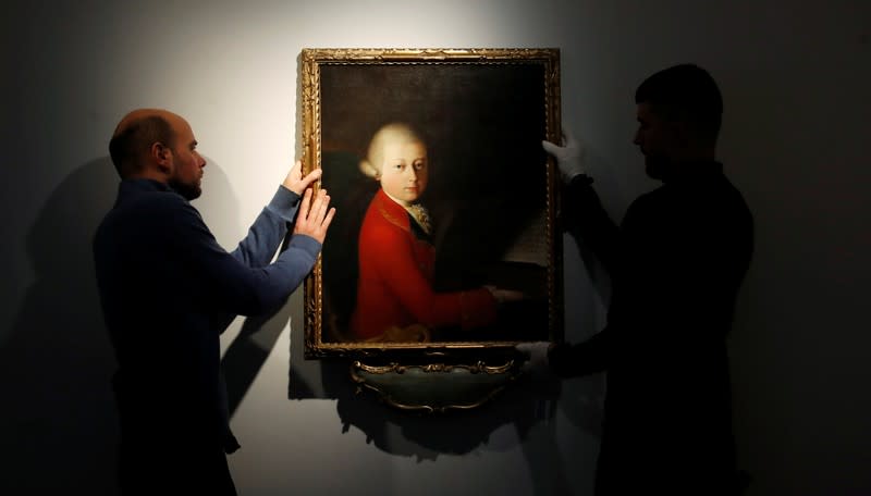 Workers install a portrait due to be sold at auction by Christie's in Paris which depicts composer Wolfgang Amadeus Mozart