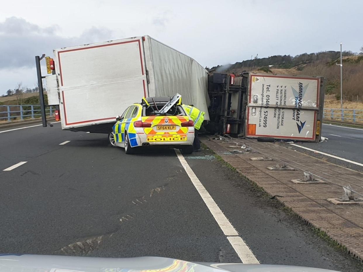 A police car was crushed by a lorry after it was blown over by strong winds on the A1 in Scotland while he was attending to another toppled HGV on 10 December, 2019: Police Scotland