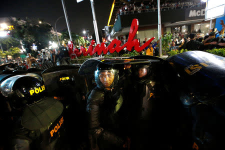 Riot police officers stand guard as people shout during a protest across the Election Supervisory Agency (Bawaslu) headquarters following the announcement of the last month's presidential election results in Jakarta, Indonesia, May 22, 2019. REUTERS/Willy Kurniawan