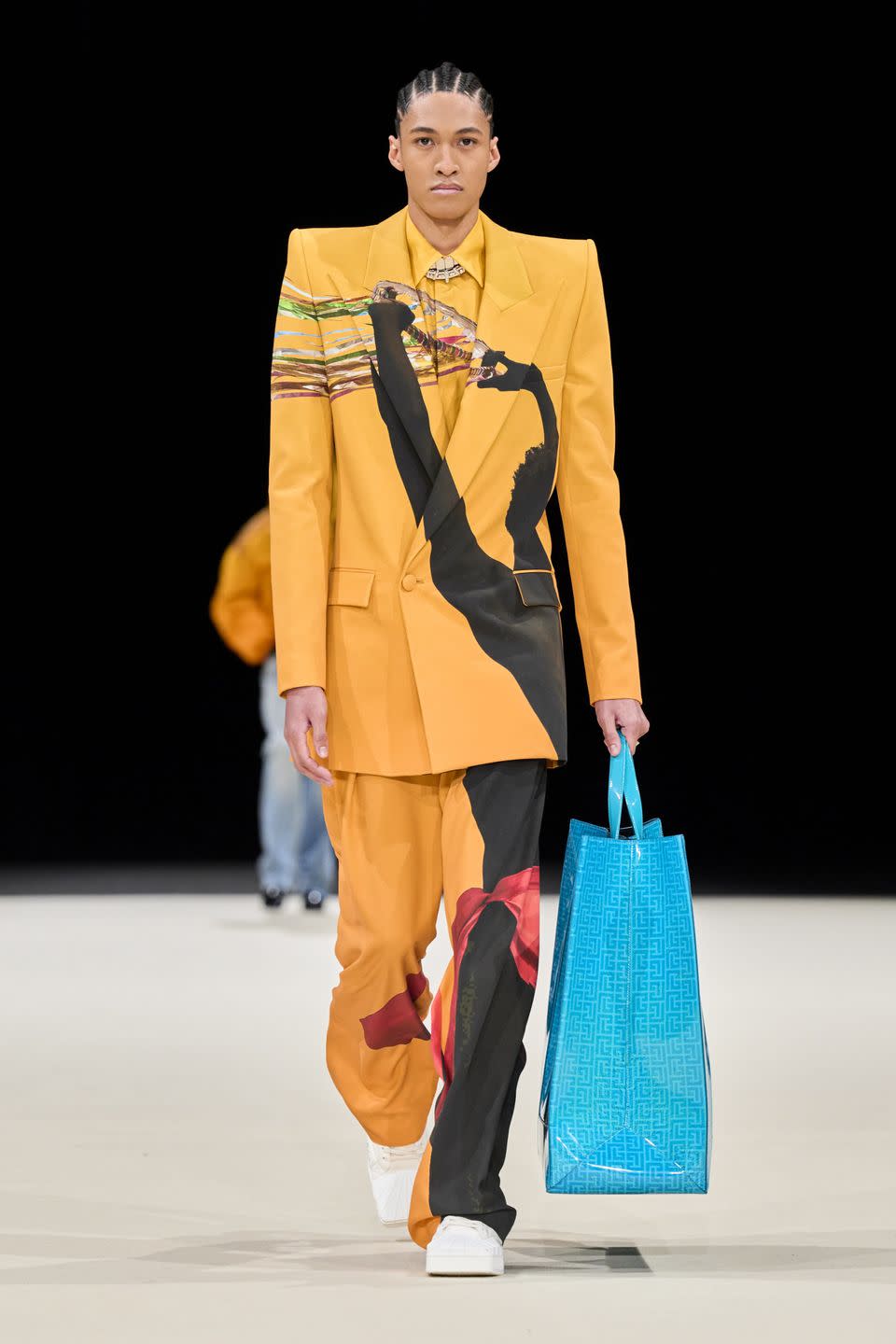 a man wearing a yellow coat and holding a blue bag