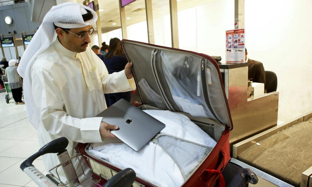 A man puts his laptop inside his suitcase at Kuwait international airport.