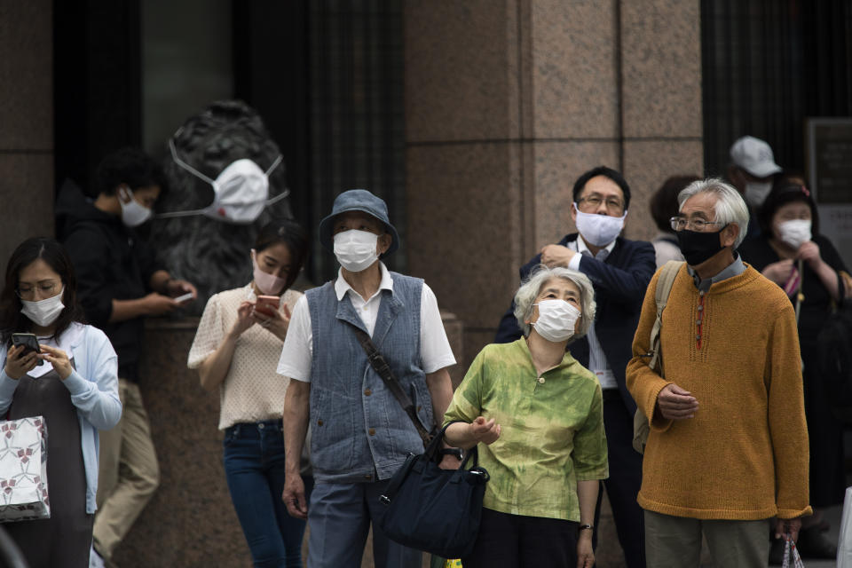 People wearing face masks, wait to walk across a traffic intersection in the famed Ginza shopping neighborhood in Tokyo on Friday, May 21, 2021. Japan has approved the use of two new vaccines - Moderna and AstraZeneca - hours ahead of an expansion of a state of coronavirus emergency that will cover roughly 40% of the population. It’s the latest effort to contain a worrying surge in infections nine weeks ahead of the opening of the Tokyo Olympics.(AP Photo/Hiro Komae)