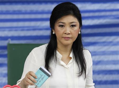 Thai Prime Minister Yingluck Shinawatra holds her ballot before casting it at a polling station in Bangkok March 30, 2014. REUTERS/Chaiwat Subprasom