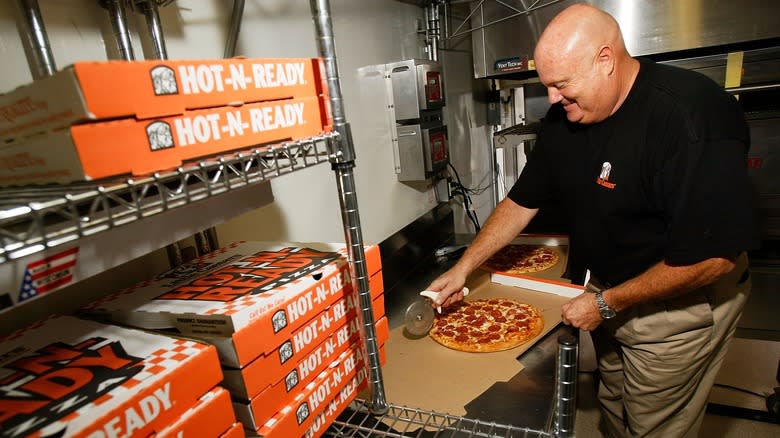 man slices pepperoni pizza