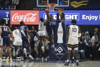 West Virginia forward Gabe Osabuohien (3) shoots while defended by Connecticut forward Isaiah Whaley (5) during the first half of an NCAA college basketball game in Morgantown, W.Va., Wednesday, Dec. 8, 2021. (AP Photo/Kathleen Batten)