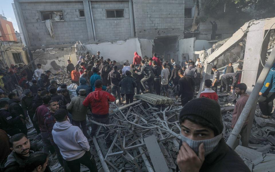 Palestinians search for bodies and survivors among the rubble of a destroyed house following Israeli airstrikes on Al Nusairat refugee camp