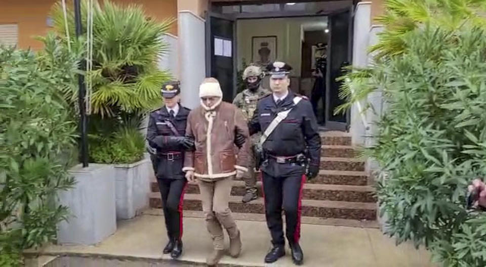 In this picture taken from a video released by Italian Carabinieri on Monday, Jan. 16, 2023, top Mafia boss Matteo Messina Denaro, center, leaves an Italian Carabinieri barrack soon after his arrest at a private clinic in Palermo, Sicily, after 30 years on the run, Monday, Jan. 16, 2023. (Carabinieri via AP)