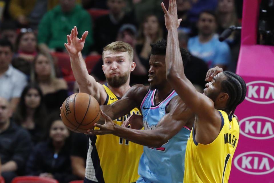 Miami Heat forward Jimmy Butler, center, loses control of the ball as he is guarded by Indiana Pacers forwards Domantas Sabonis, left, and T.J. Warren during the first half of an NBA basketball game Friday, Dec. 27, 2019, in Miami. (AP Photo/Wilfredo Lee)