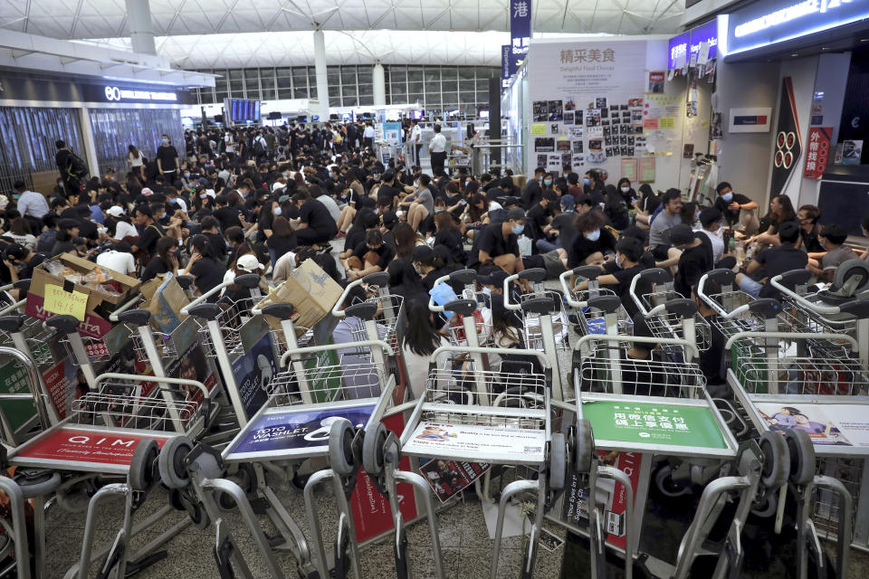 Protesters use luggage trolleys to block the walkway to the departure gates during a demonstration at the Airport in Hong Kong, Tuesday, Aug. 13, 2019. (Photo: Vincent Yu/AP)