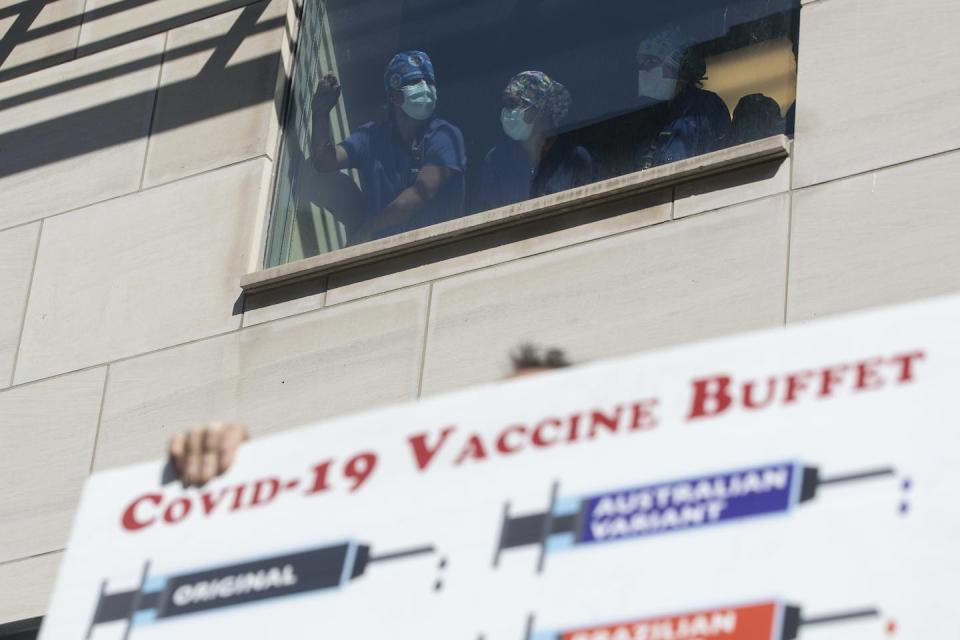 Health-care workers watch from a window as demonstrators gather outside Toronto General Hospital, in September 2021, to protest against COVID-19 vaccines. THE CANADIAN PRESS/Chris Young