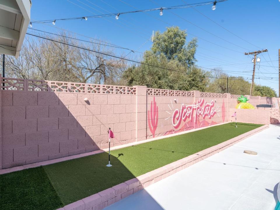 A mini golf run in front of a pink wall.