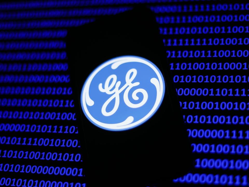 General Electric logo displayed on a phone screen and a binary code displayed on a screen are seen in this illustration photo taken in Krakow, Poland on January 15, 2023.