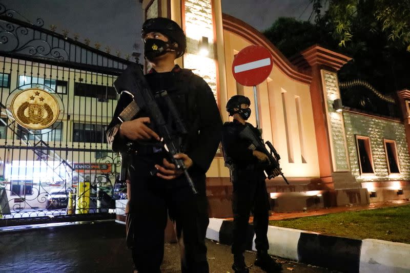 Armed police officers stand guard at the gate of national police headquarters, in Jakarta