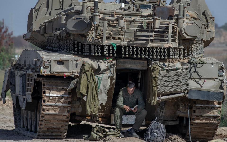 An Israeli soldier sits in a Merkava tank and reads a book