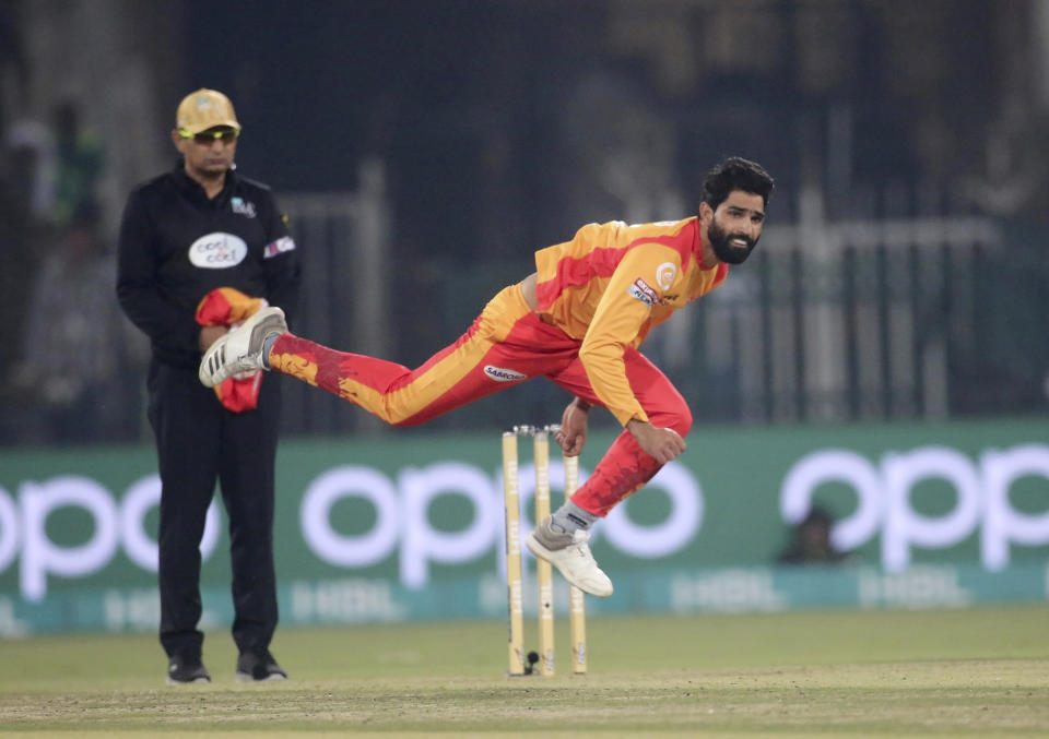 Islamabad United pacer Amad Butt, front, bowls while umpire Shozab Raza watches during their Pakistan Super League T20 cricket match at Gaddafi stadium in Lahore, Pakistan, Saturday, Feb. 22, 2020. (AP Photo/K.M. Chaudary)