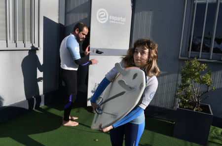 Carmen Lopez Garcia, Spain's first blind female surfer who is to participate in the ISA World Adaptive Surfing Championship, holds her surfboard as she waits for her coach Lucas Garcia before training at Salinas beach, Spain, December 6, 2018. REUTERS/Eloy Alonso