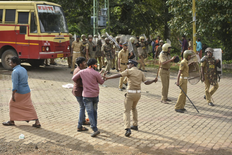 Un policía utiliza su garrote contra manifestantes que intentan prohibir a mujeres en edad de menstruar entrar al templo Sabarimala en Nilackal, un campo base camino al santuario en la montaña en Kerala, India, el miércoles 17 de octubre de 2018. (AP Foto)