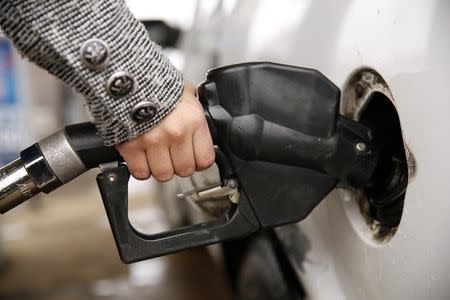 A woman pumps gas at a station in Falls Church, Virginia December 16, 2014. REUTERS/Kevin Lamarque