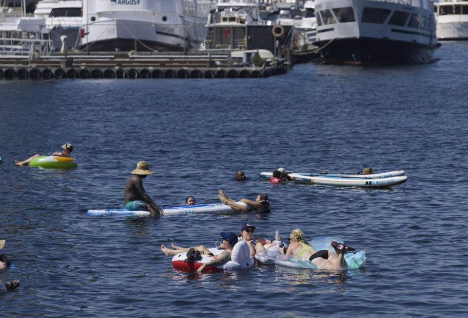 Groups of people float on inflatable devices on Lake Union during a heat wave hitting the Pacific Northwest, Sunday, June 27, 2021, in Seattle. A day earlier, a record high was set for that date with more record highs expected today and Monday. (AP Photo/John Froschauer)