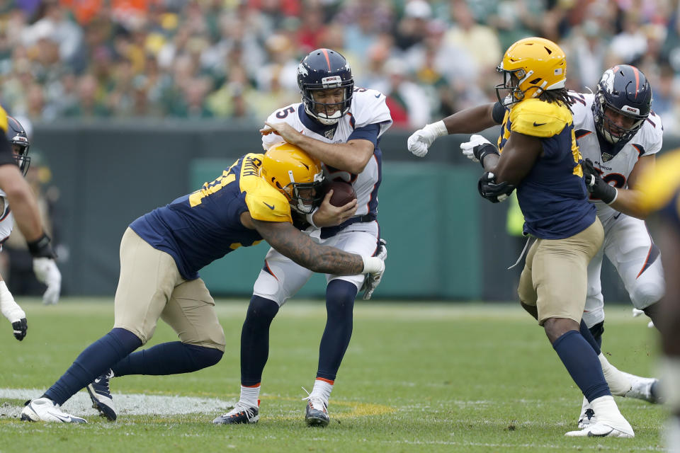 Denver Broncos quarterback Joe Flacco, center, is hit by Green Bay Packers outside linebacker Preston Smith, left, as Packers' linebacker Rashan Gary, right, watches during the first half of an NFL football game Sunday, Sept. 22, 2019, in Green Bay, Wis. (AP Photo/Matt Ludtke)