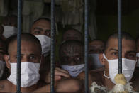 Imprisoned gang members, wearing protective face masks, look out from behind bars during a media tour of the prison in Quezaltepeque, El Salvador, Friday, Sept. 4, 2020. President Nayib Bukele denied a report Friday that his government has been negotiating with one of the country’s most powerful gangs to lower the murder rate and win their support in mid-term elections in exchange for prison privileges. (AP Photo/Salvador Melendez)