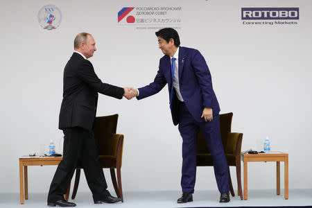 Russian President Vladimir Putin (L) shakes hands with Japanese Prime Minister Shinzo Abe during a Japanese-Russian business dialogue meeting in Tokyo, Japan, December 16, 2016. Sputnik/Michael Klimentyev/Kremlin/via REUTERS