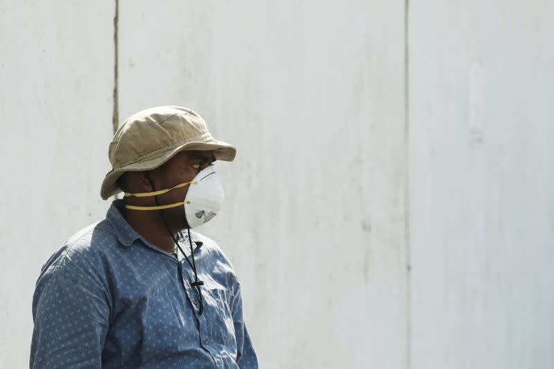 A man wearing a face mask waits to see a relative who is admitted after being affected from a suspected gas leak, at a hospital premises in Karachi