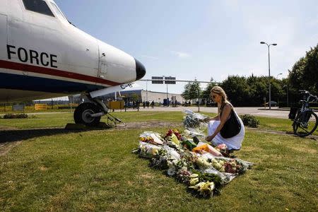 A local woman lays a bouquet of flower on the grass in front of a Dutch airplane during a national day of mourning for the victims killed in Malaysia Airlines Flight MH17 plane disaster last Thursday, in Eindhoven July 23, 2014. REUTERS/Mischa Rapmund