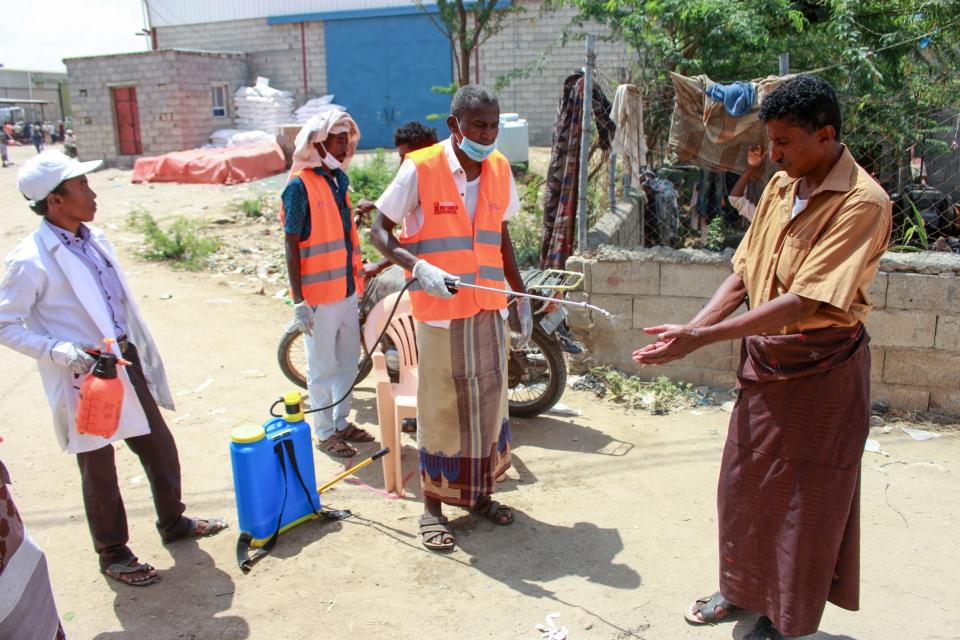 Employees of the World Food Programme (WFP) spray the hands of a displaced Yemeni man with disinfectant: AFP via Getty Images