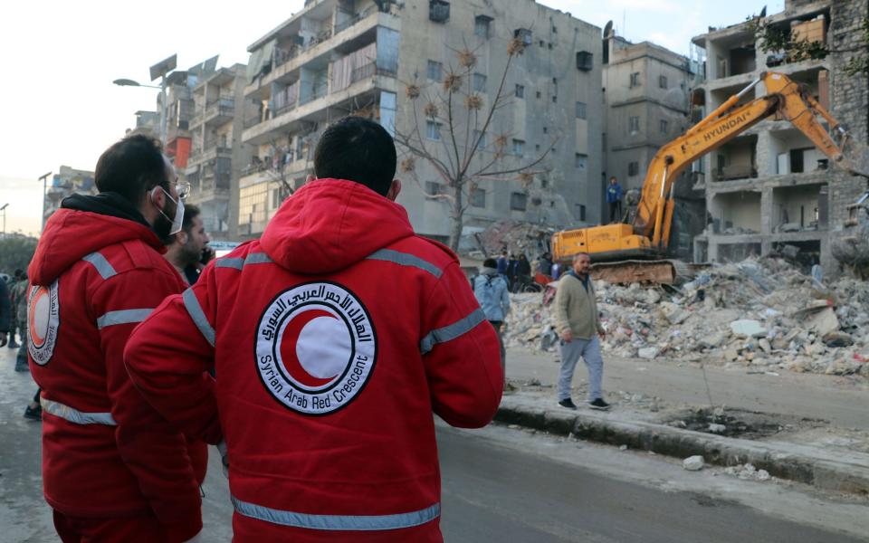 Two members of the Syrian Red Crescent watch rescue workers at Masharqa neighborhood of Aleppo - STRINGER/EPA-EFE/Shutterstock