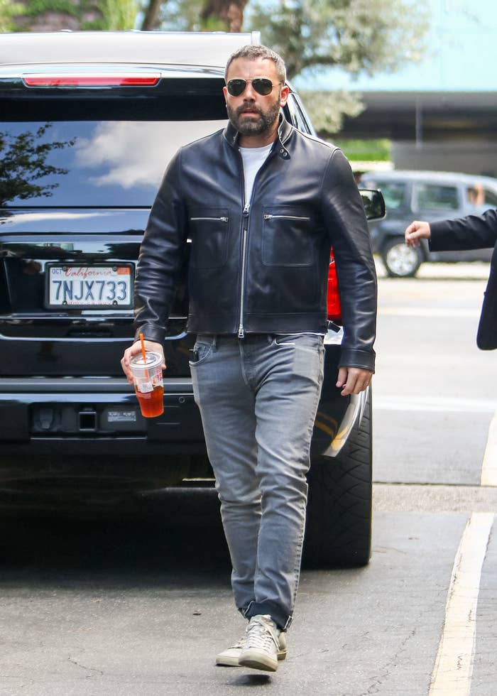 ben walking outside holding a large iced coffee