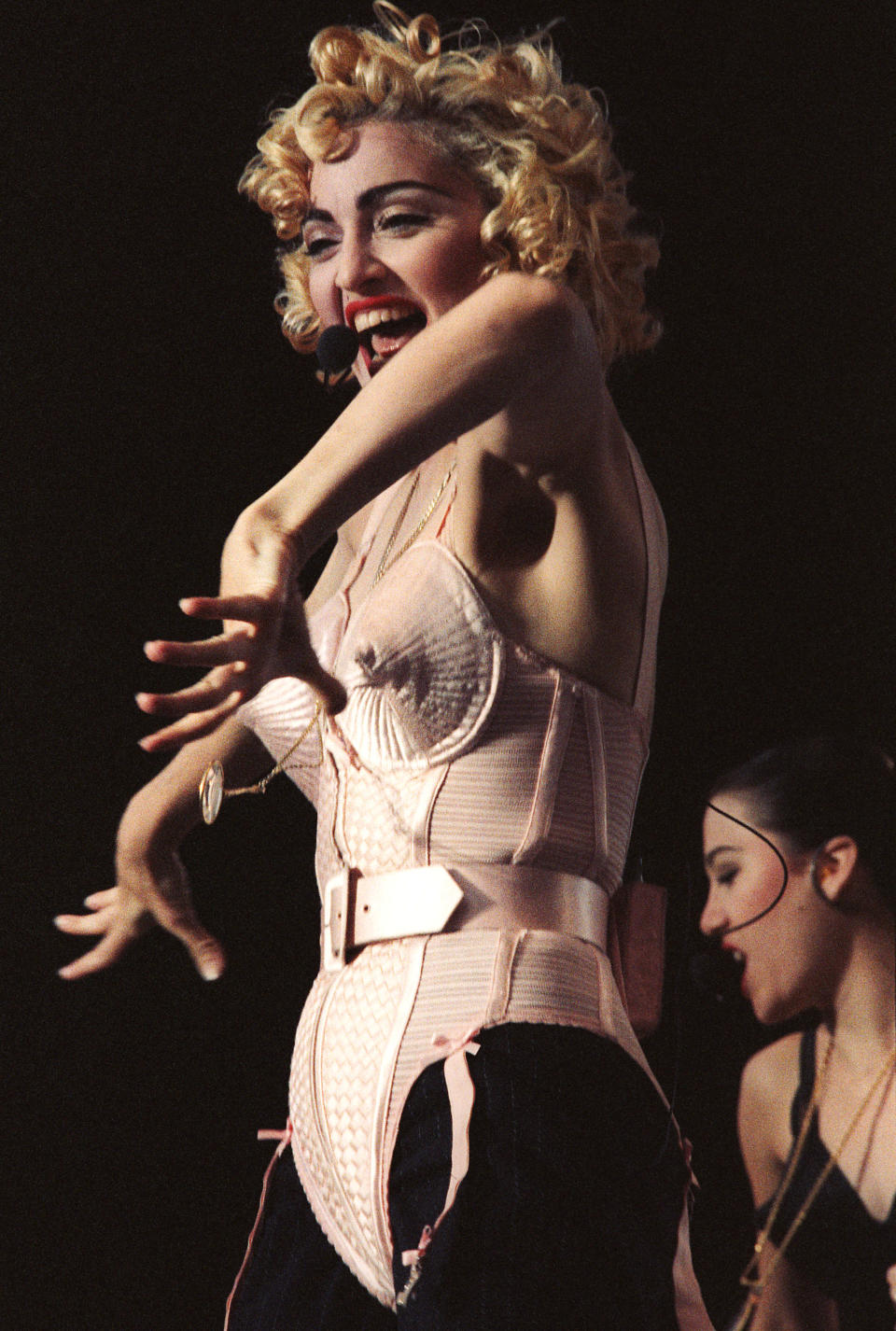 Pop star Madonna sings in pink corset and black stockings with blonde curly hair.